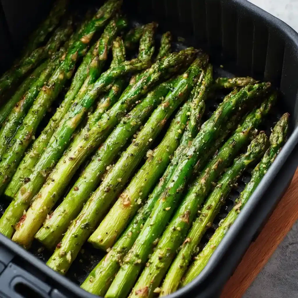 Asperges au Airfryer : Croustillantes et Tendres en 8 Minutes 7 Asperges vertes assaisonnées disposées en une seule couche dans le panier d'un airfryer